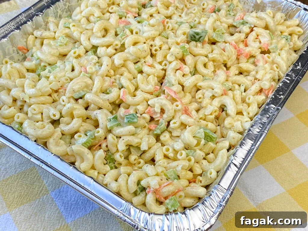 Close up of easy and creamy macaroni salad for a crowd in foil pan on yellow plaid napkin
