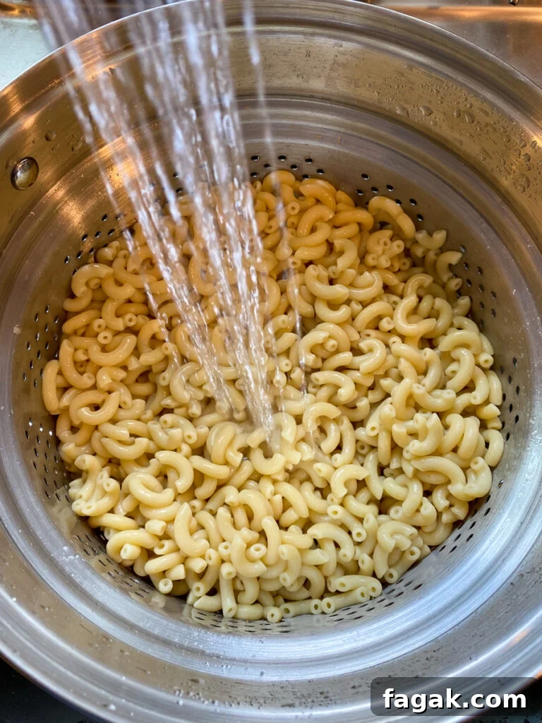 Rinsing cooked macaroni in a strainer under cold running water