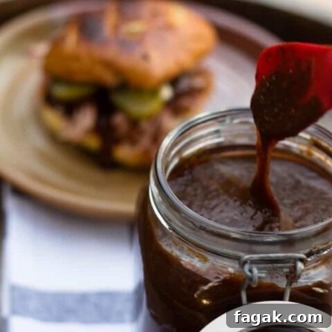 pumpkin spice bbq sauce dripping from utensil and pulled pork sandwich in background