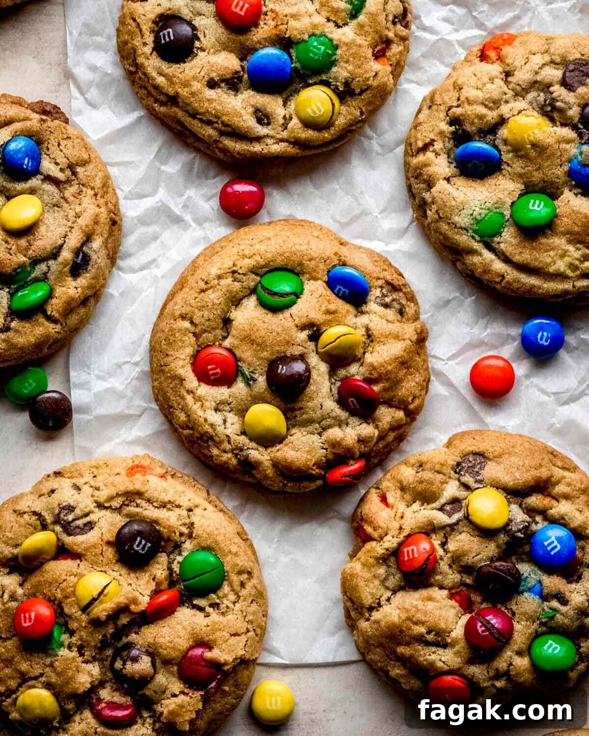 Baked chocolate chip M&M cookies cooling on parchment paper.