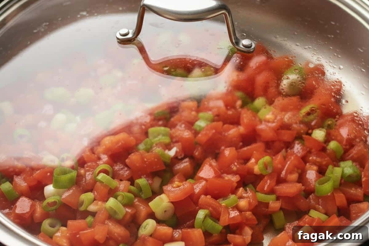 Diced tomatoes with green onions in a saucepan with lid.