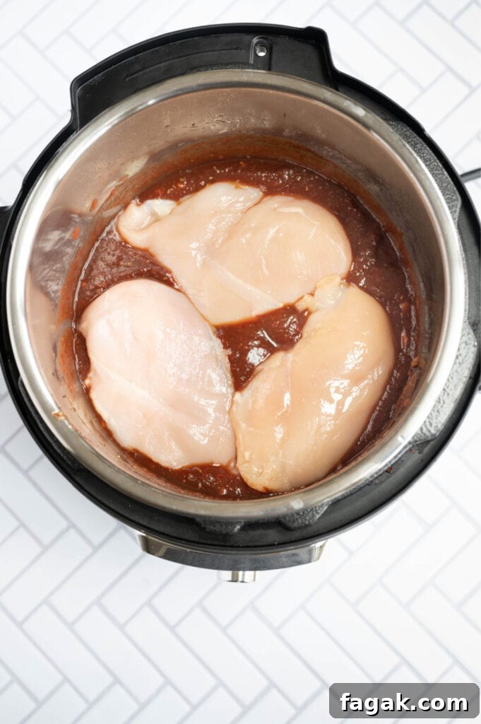 Overhead photo of an Instant Pot full of balsamic chicken ingredients, including chicken on the top.