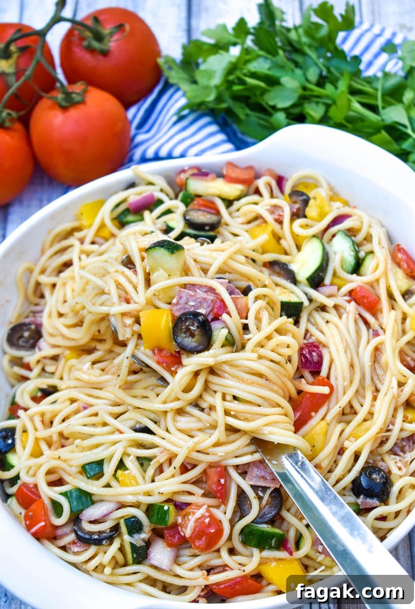 a metal spoon lifting Italian spaghetti salad out of a white mixing bowl