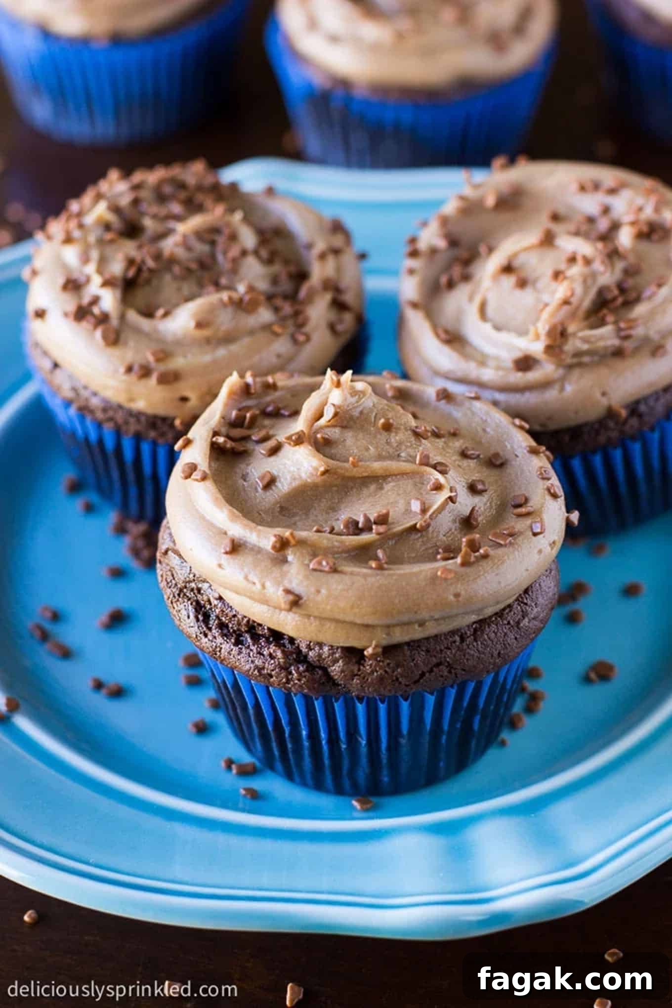 Cupcakes on a plate with chocolate buttercream frosting and bits of chocolate sprinkles on top.