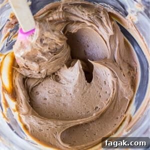 Chocolate frosting in a bowl with a spatula stirring it.