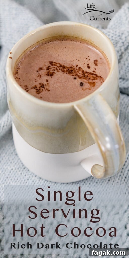 A mug filed with hot cocoa on a light blue knitted cloth 