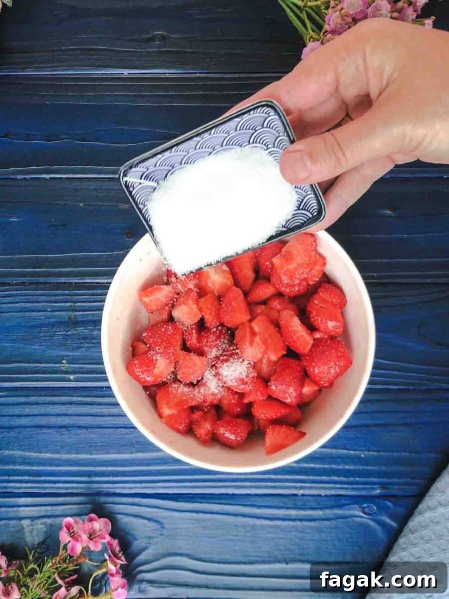 Adding the granulated sugar to the chopped strawberries.
