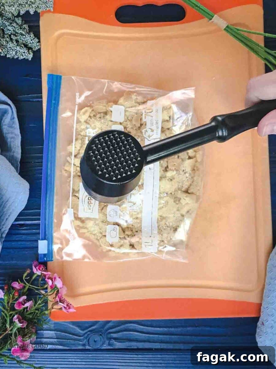 Crushing shortbread cookies in a ziplock bag. Using a meat tenderizer and a chopping board for support.