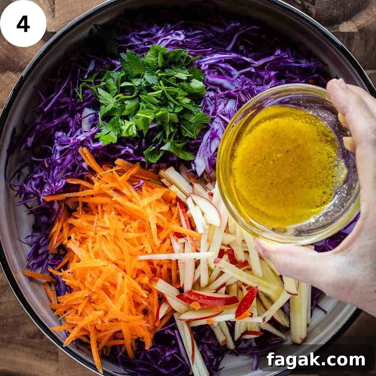 Pouring dressing onto a salad of red cabbage, carrot, and apple.