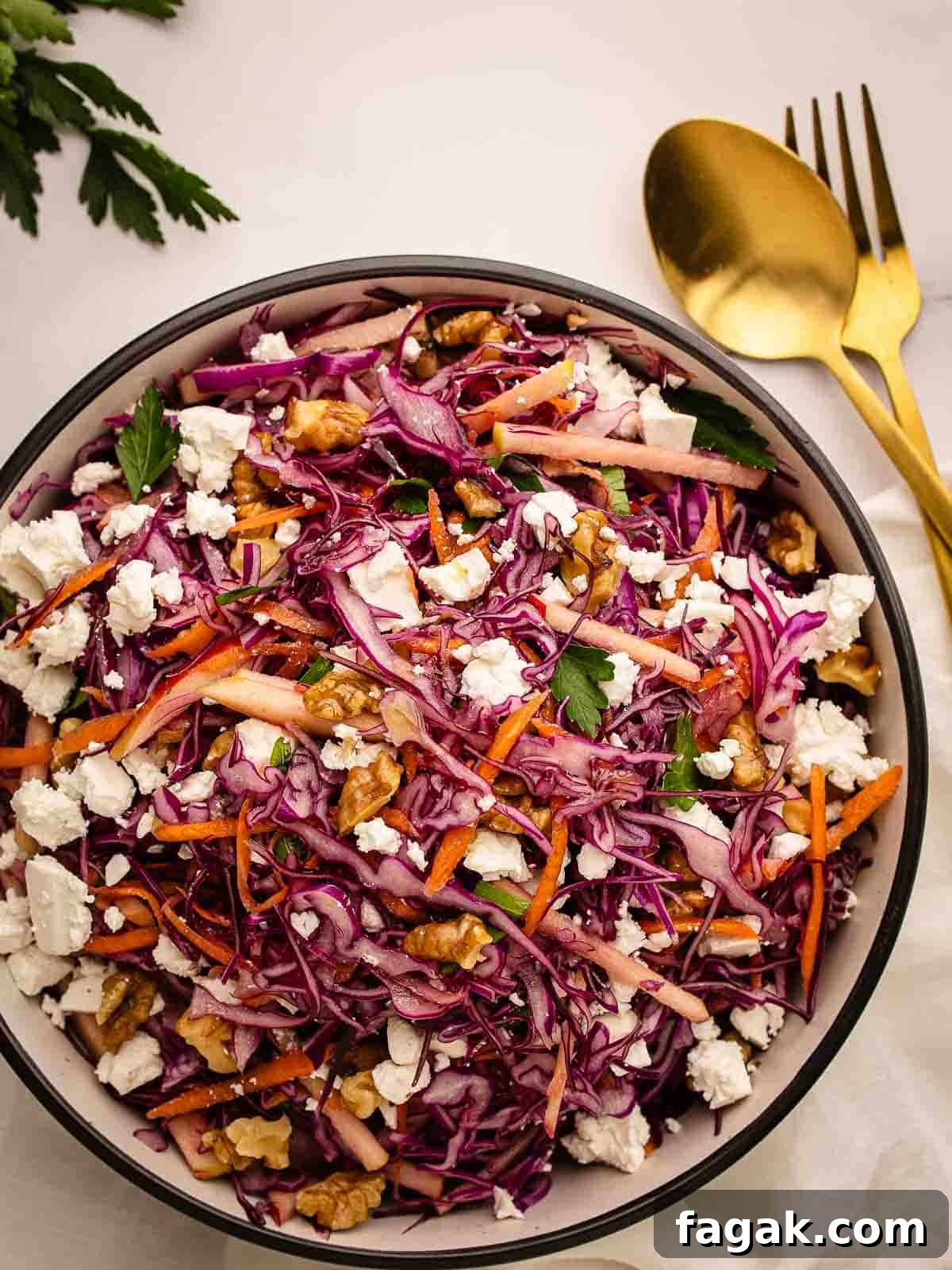 Overhead view of a salad of red cabbage, carrot and apple in a round bowl.