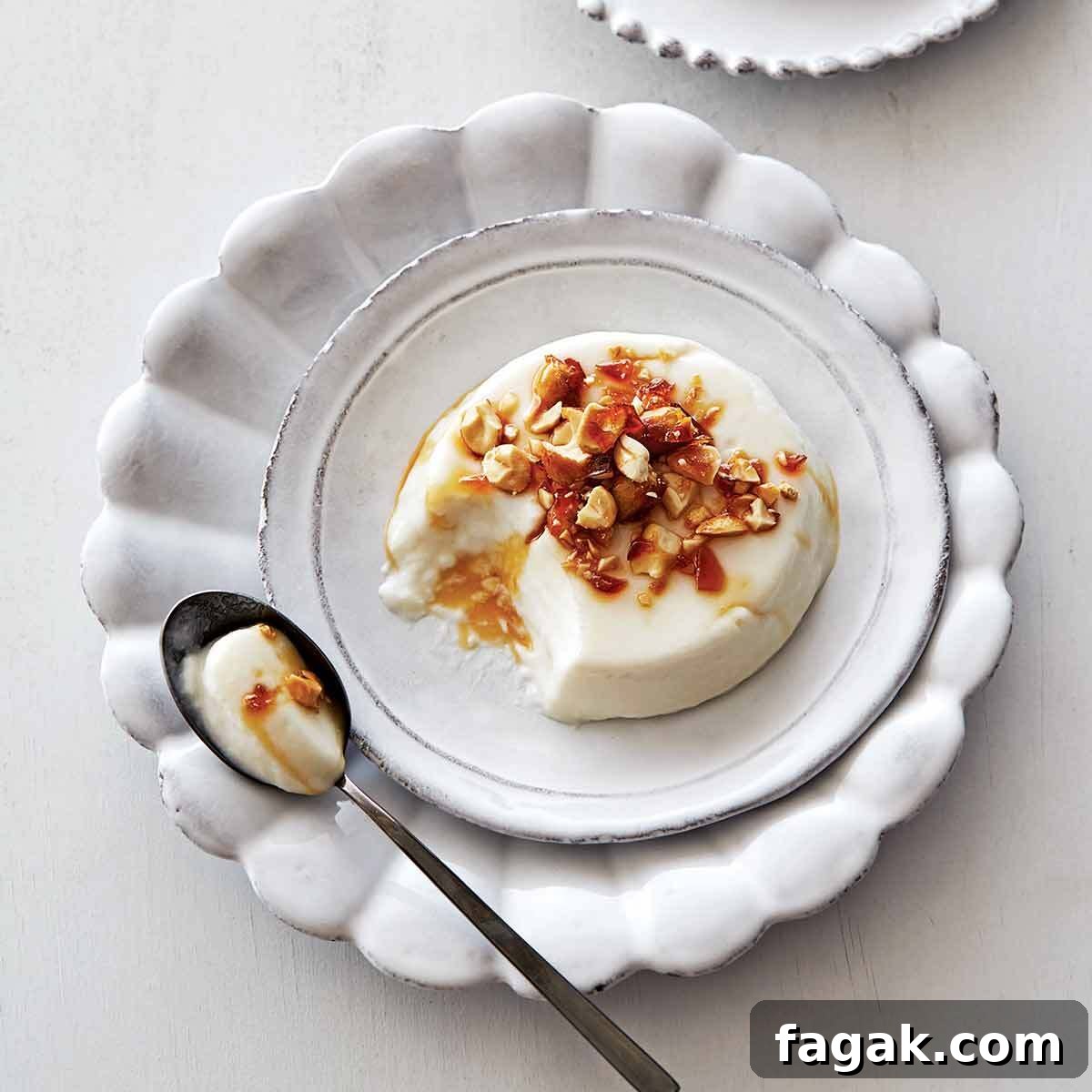 A coconut panna cotta topped with peanut brittle crunch on a white plate.