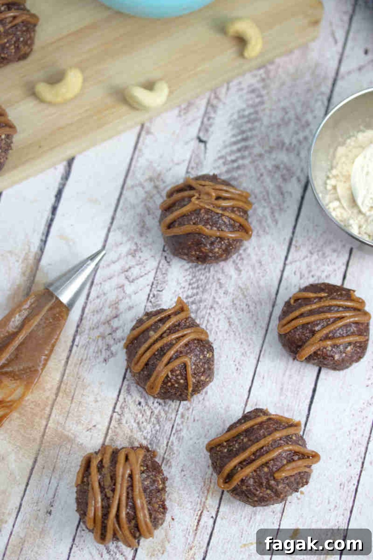 Paleo Dark Chocolate Bliss Balls Recipe for Quick Snacks 2 Chocolate balls with dairy-free caramel sauce piped onto them.