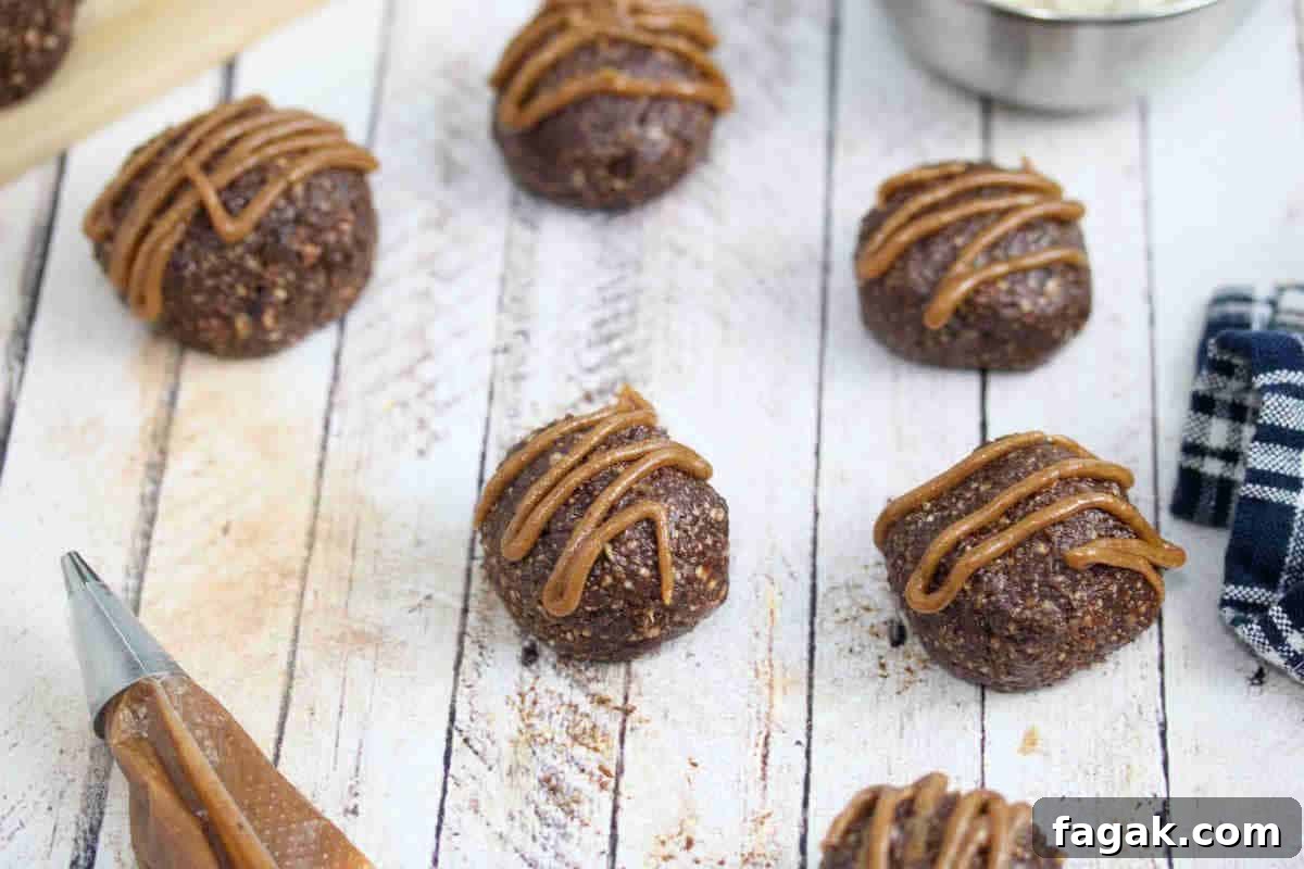 Paleo Dark Chocolate Bliss Balls Recipe for Quick Snacks 16 Chocolate balls with dairy-free caramel sauce piped onto them.