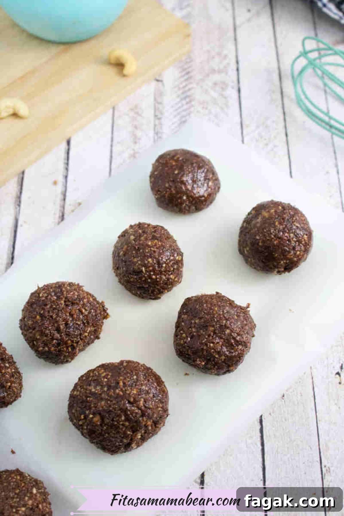 Paleo Dark Chocolate Bliss Balls Recipe for Quick Snacks 8 Chocolate bliss balls in a line on parchment paper.