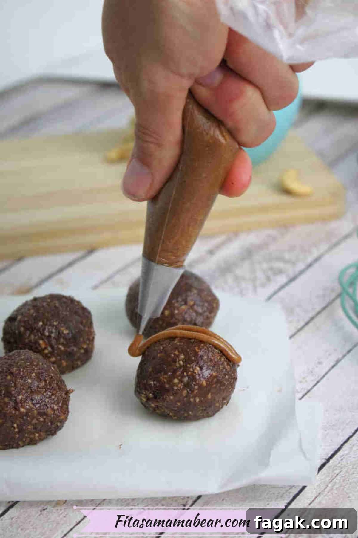 Paleo Dark Chocolate Bliss Balls Recipe for Quick Snacks 9 Caramel being piped onto chocolate energy balls on parchment paper.
