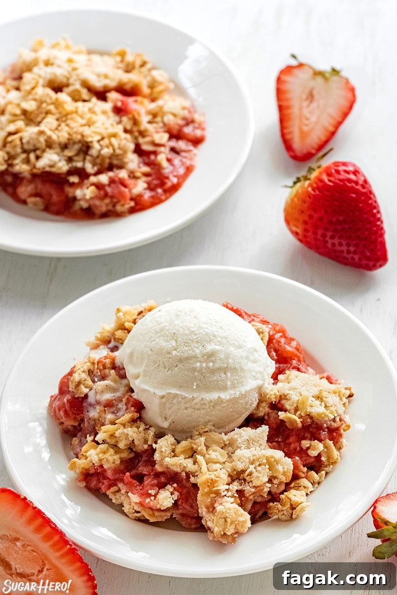 Two servings of Strawberry Crisp in white bowls with vanilla ice cream.