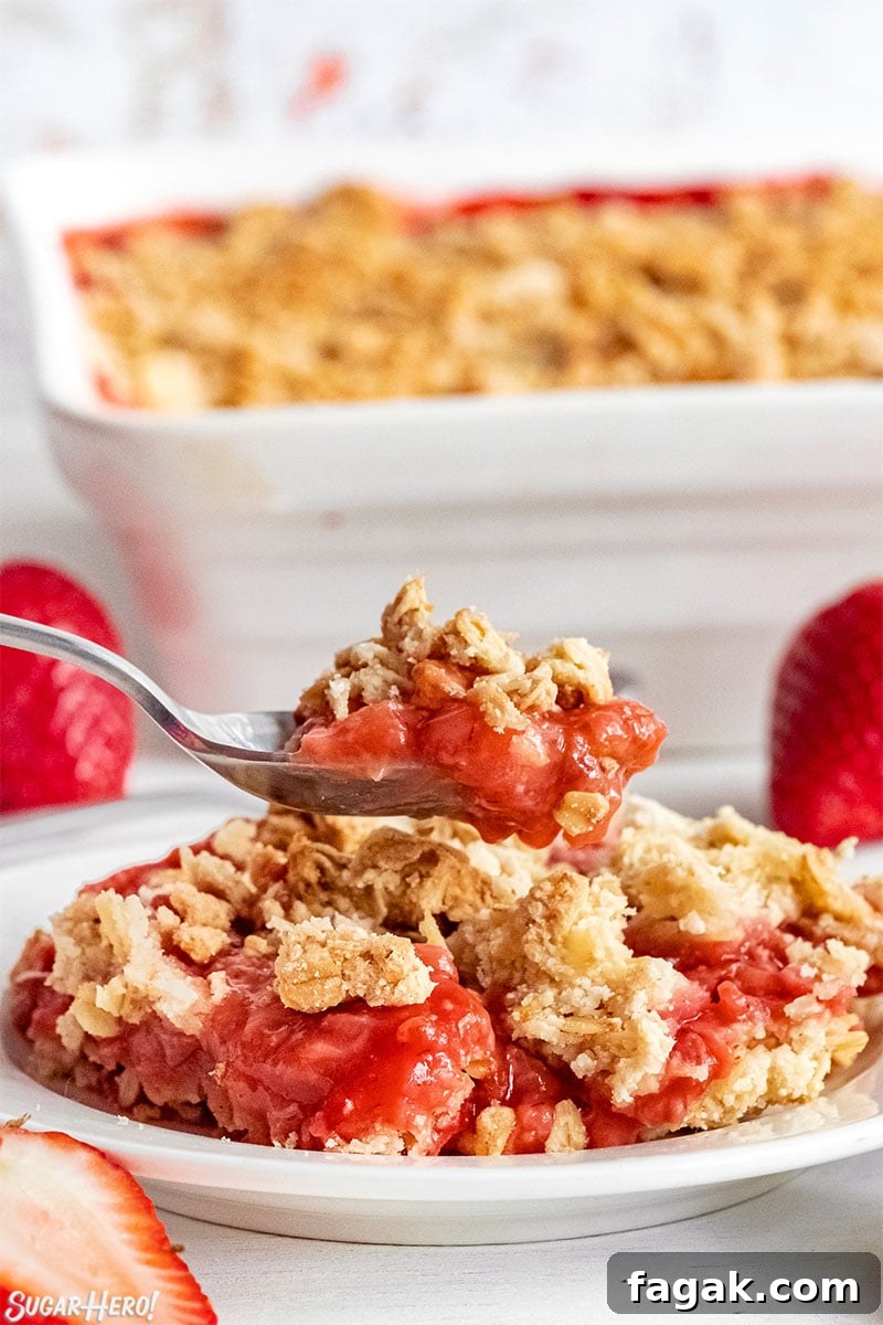 Spoon serving up a scoop of Strawberry Crisp on a white plate.