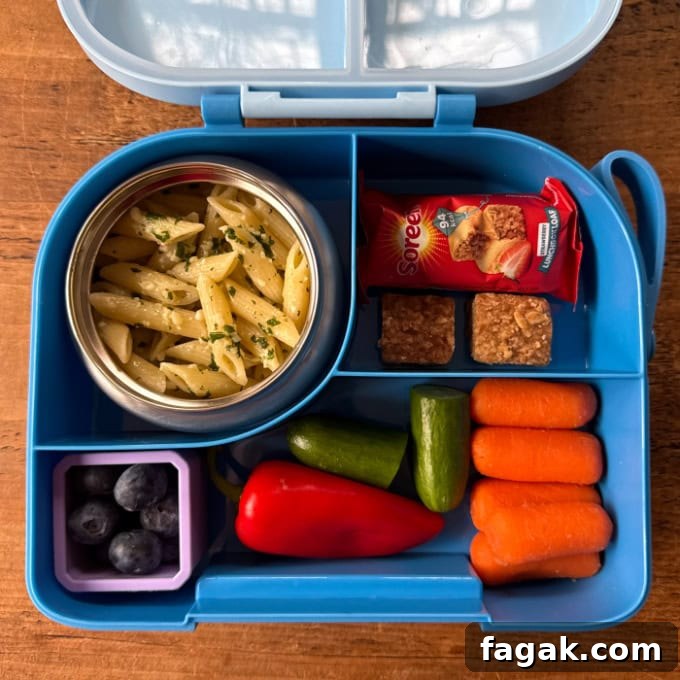 Nut Free Pesto Pasta served in a bright blue hot & cold lunchbox, served with chopped fresh veggies.