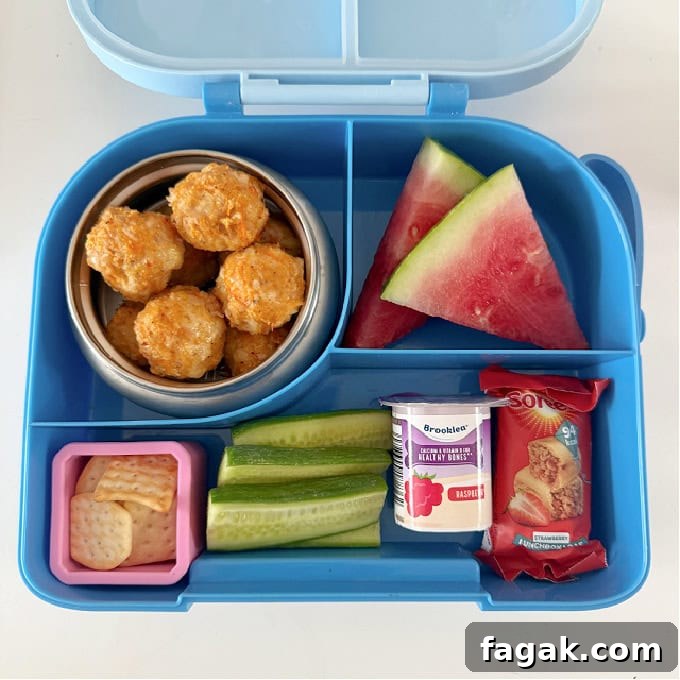 Chicken Sausage bites in a bright blue hot & cold lunch box, served with chunks of watermelon, and other treats.