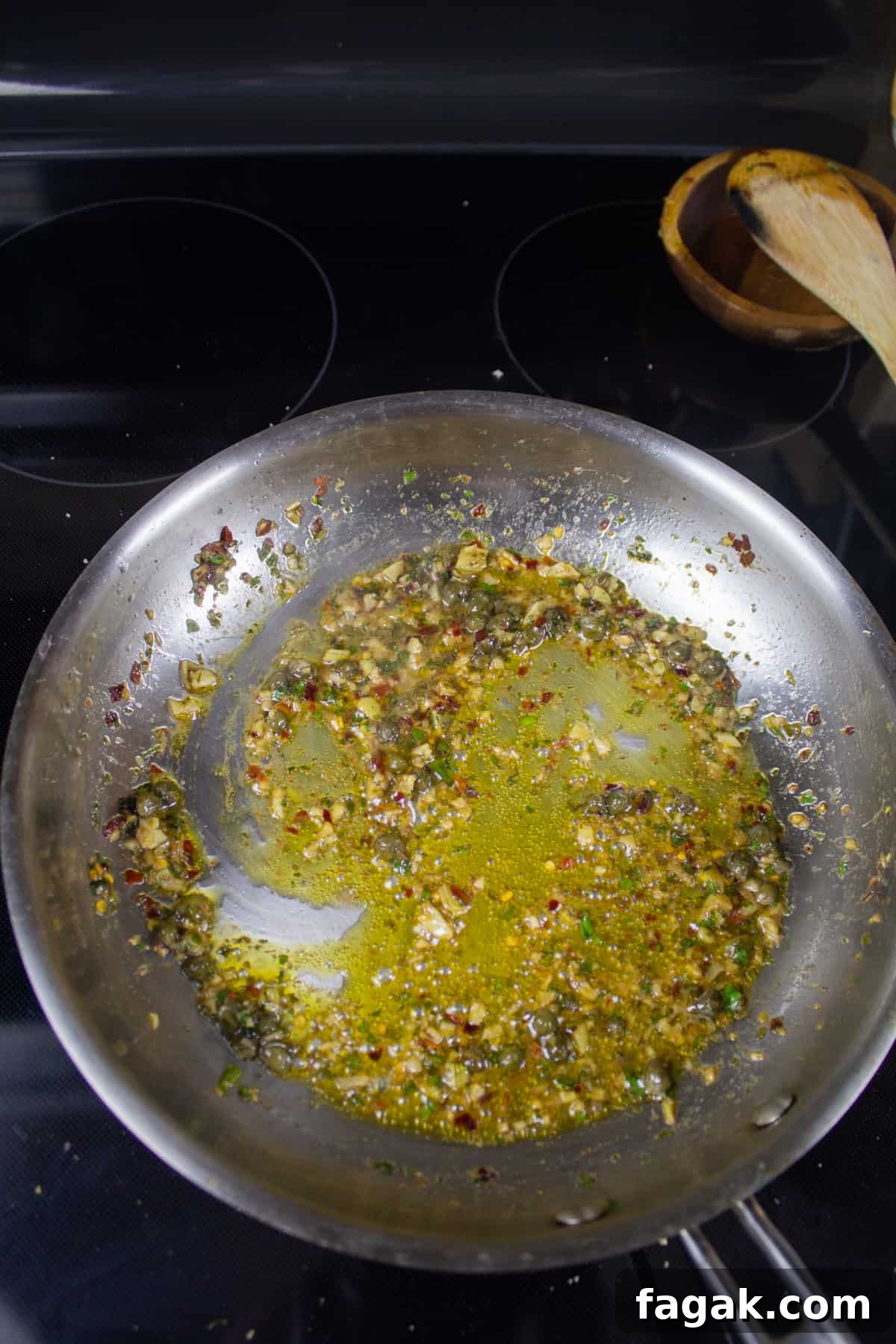 Garlic, Anchovy, capers, and parsley in olive oil in a pan on the stove