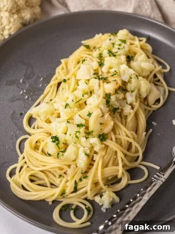 spaghetti with cauliflower plated on a dish garnished with parsley.