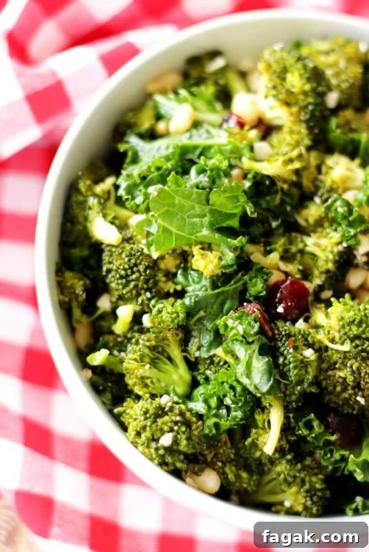 White bowl containing a kale and broccoli salad sitting on a red and white gingham napkin.