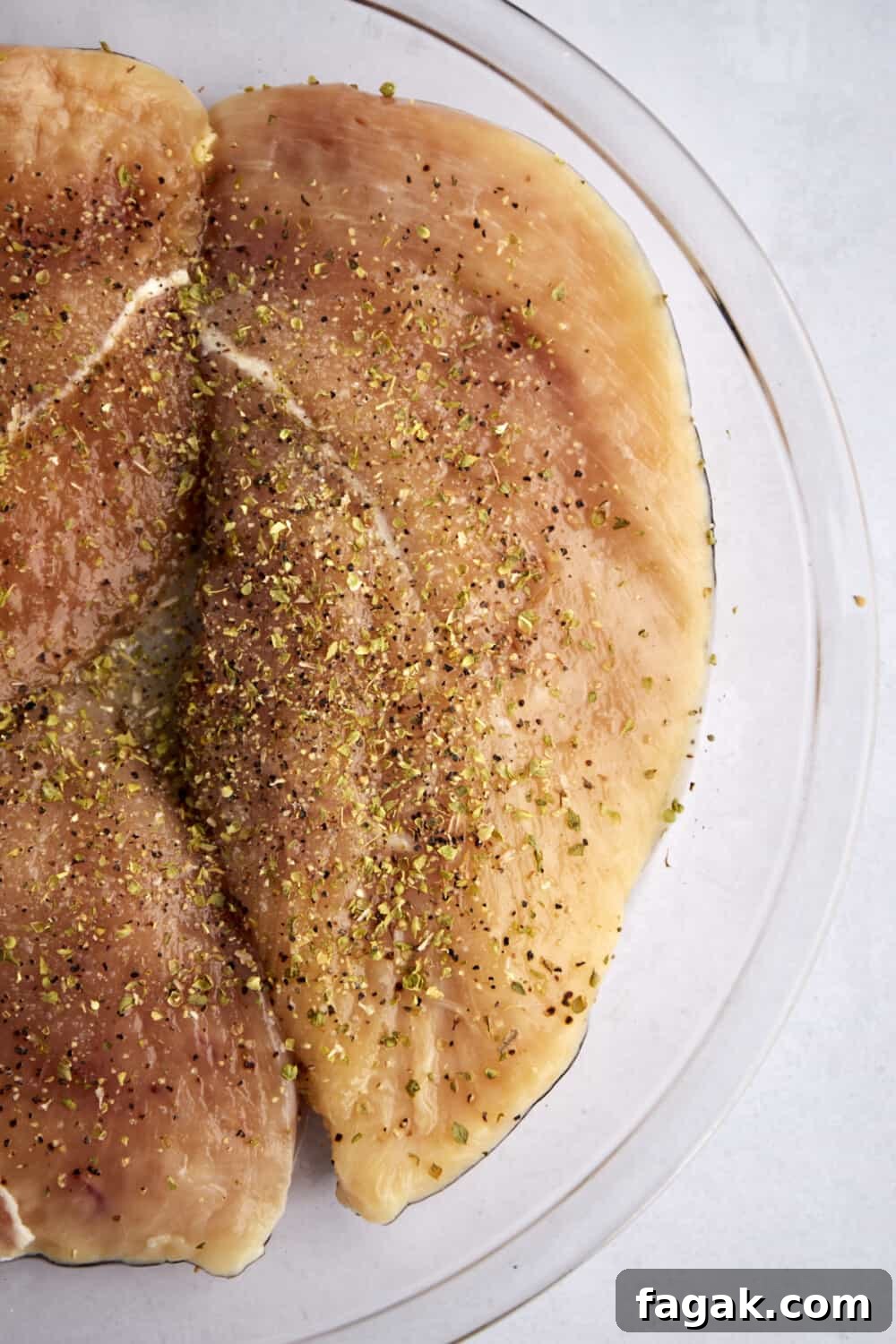 raw seasoned chicken breasts in a glass bowl