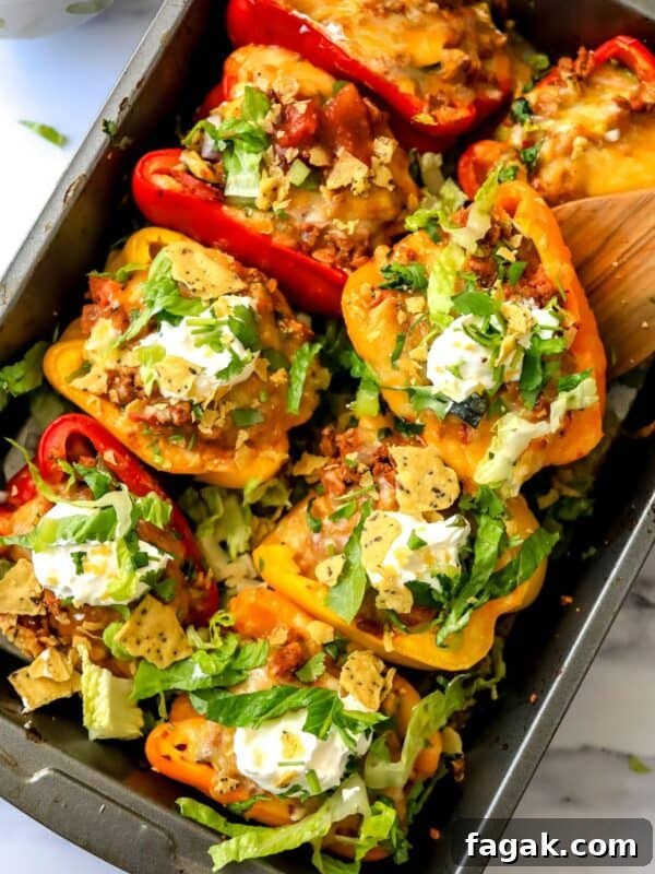 Baking dish with taco stuffed peppers in it and a wooden spatula.