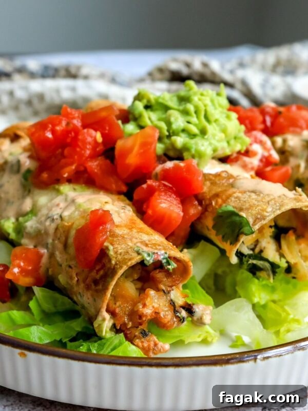 Baked Chicken Taquitos on a plate with toppings.