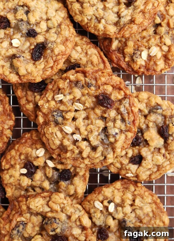 chewy oatmeal raisin cookies piled up on a cooling rack
