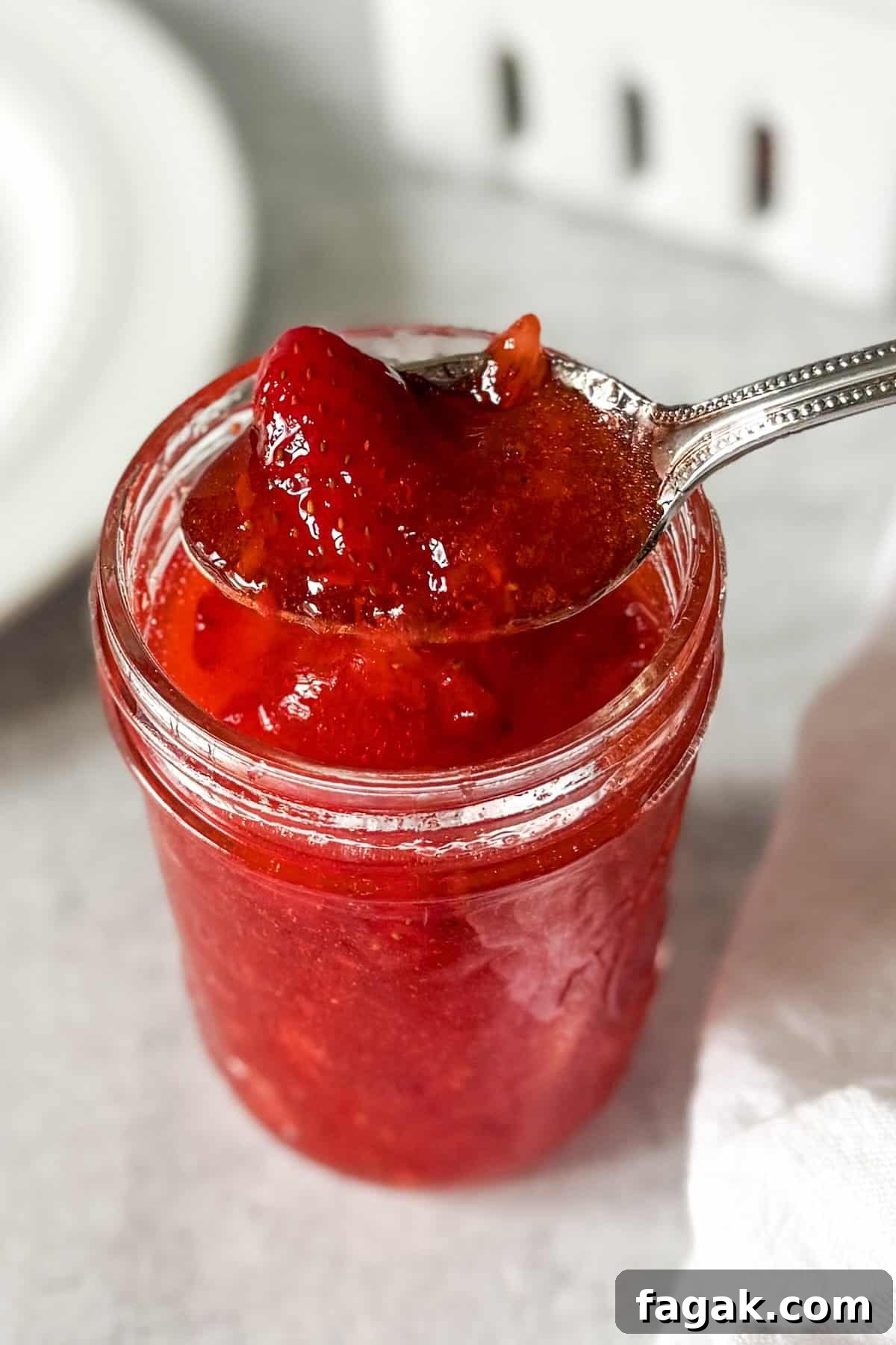A spoonful of easy strawberry freezer jam recipe with fresh strawberries.