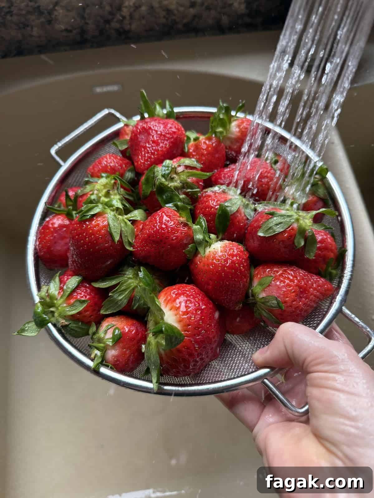 Rinsing ripe strawberries in a strainer.