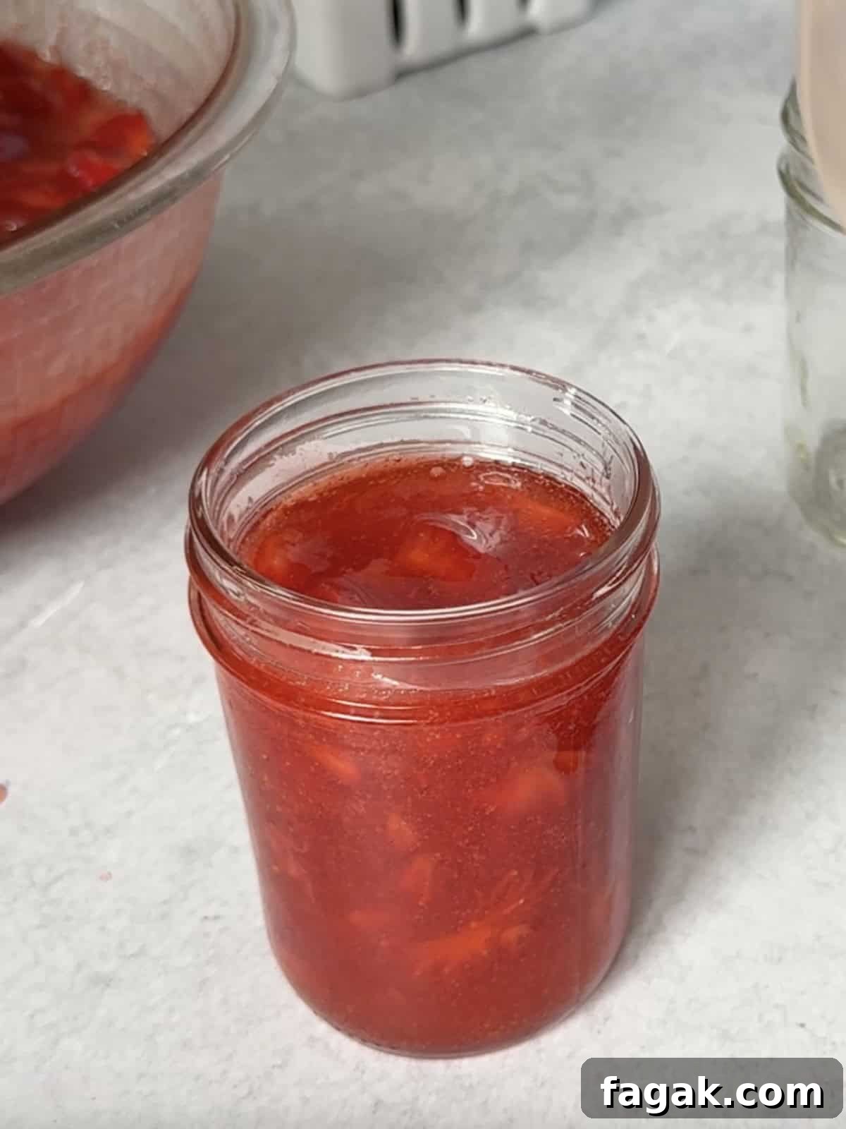 Spooning strawberry freezer jam into jars, leaving ½ inch headspace.