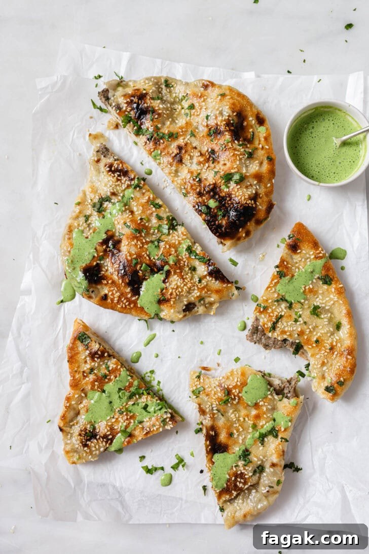 Foolproof Keema Naan Recipe: Step-by-Step Guide for Perfect Stuffed Bread 18 Slices of Keema Naan on parchment drizzled with raita.