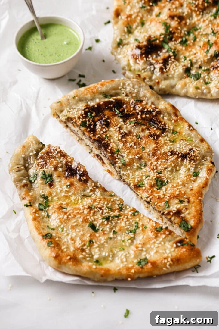 Foolproof Keema Naan Recipe: Step-by-Step Guide for Perfect Stuffed Bread 19 Baked Keema Naan cut in half and sprinkled with cilantro with raita on the side for dipping.