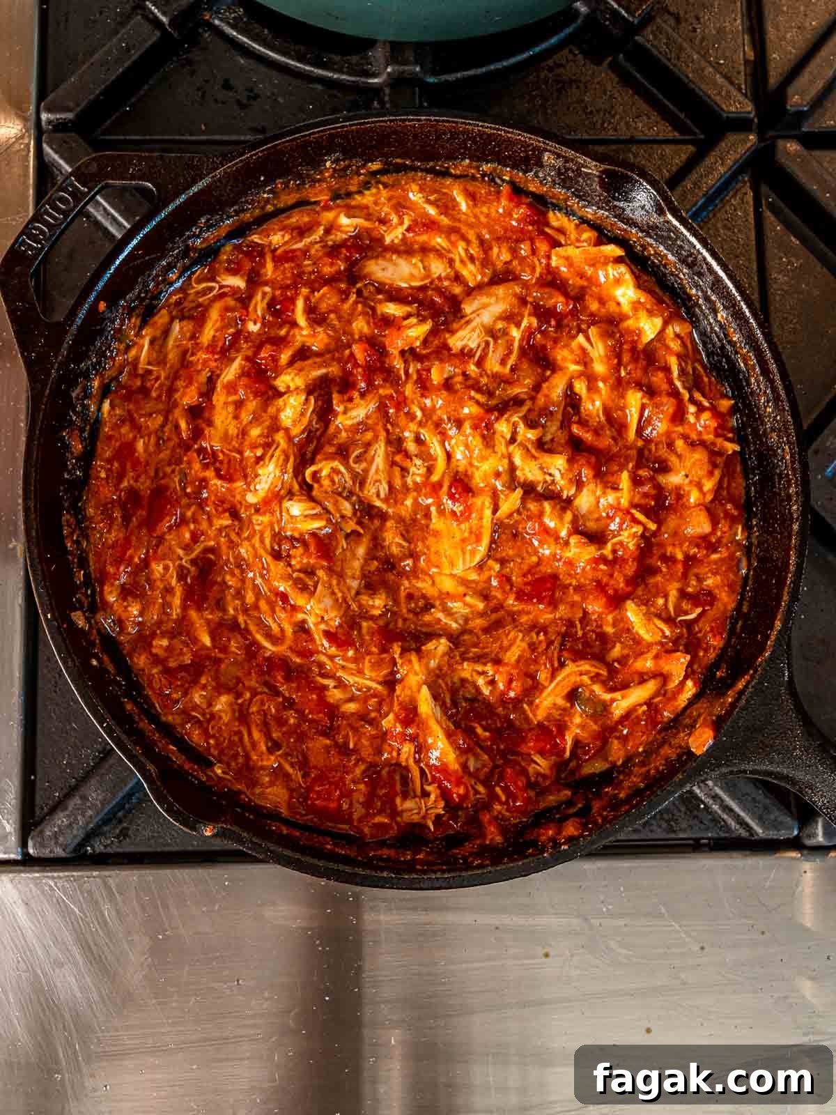 Cheesy Baked Chicken Enchilada Dip Without Cream Cheese 6 Shredded chicken in a skillet of enchilada sauce and seasonings.