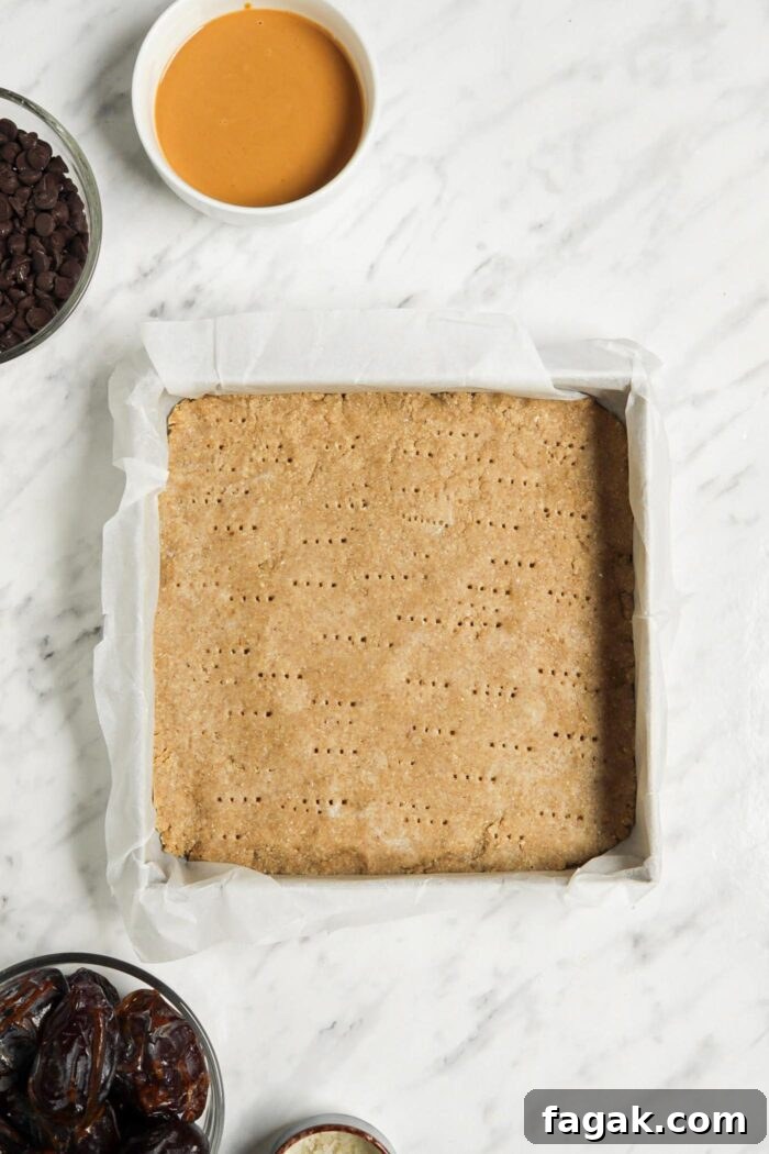 Baked shortbread crust in a baking pan lined with parchment paper.