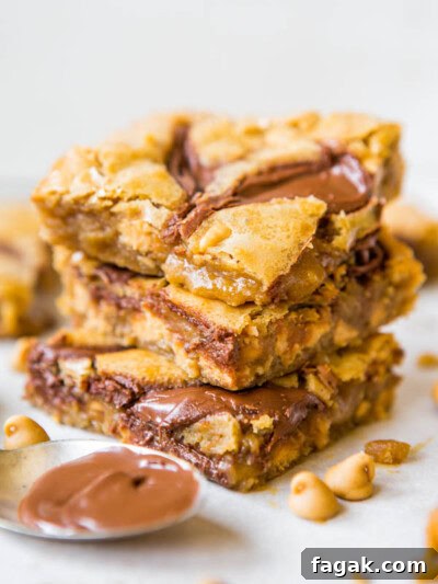 Stack of peanut butter chocolate chip blondies on a white surface.