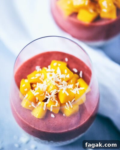 Guava strawberry chia pudding in a glass with chopped mango on top
