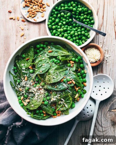 Mixed serving bowl of pea and pesto pasty with serving spoons on a wooden table
