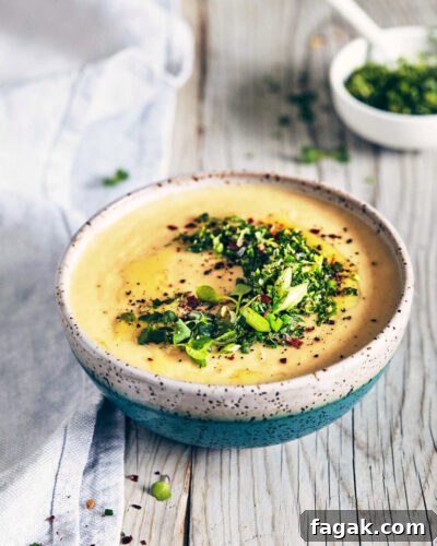 Side view of potato parsnip and leek soup with chive gremolata on a wooden surface