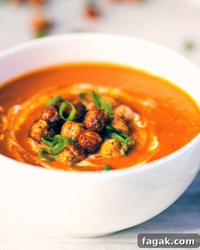 Side view of tomato ginger soup topped with crispy chickpeas and scallions