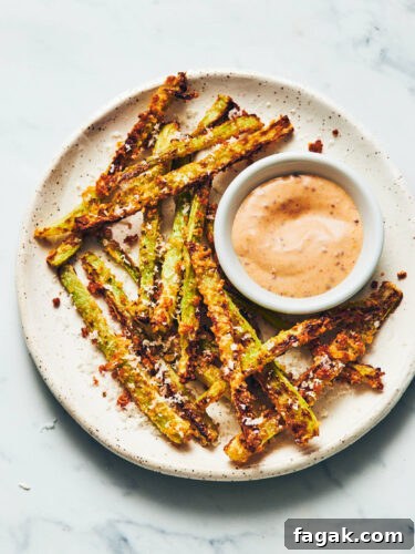 Plate of air fryer broccoli fries and vegan dijon aioli sitting on a marble counter