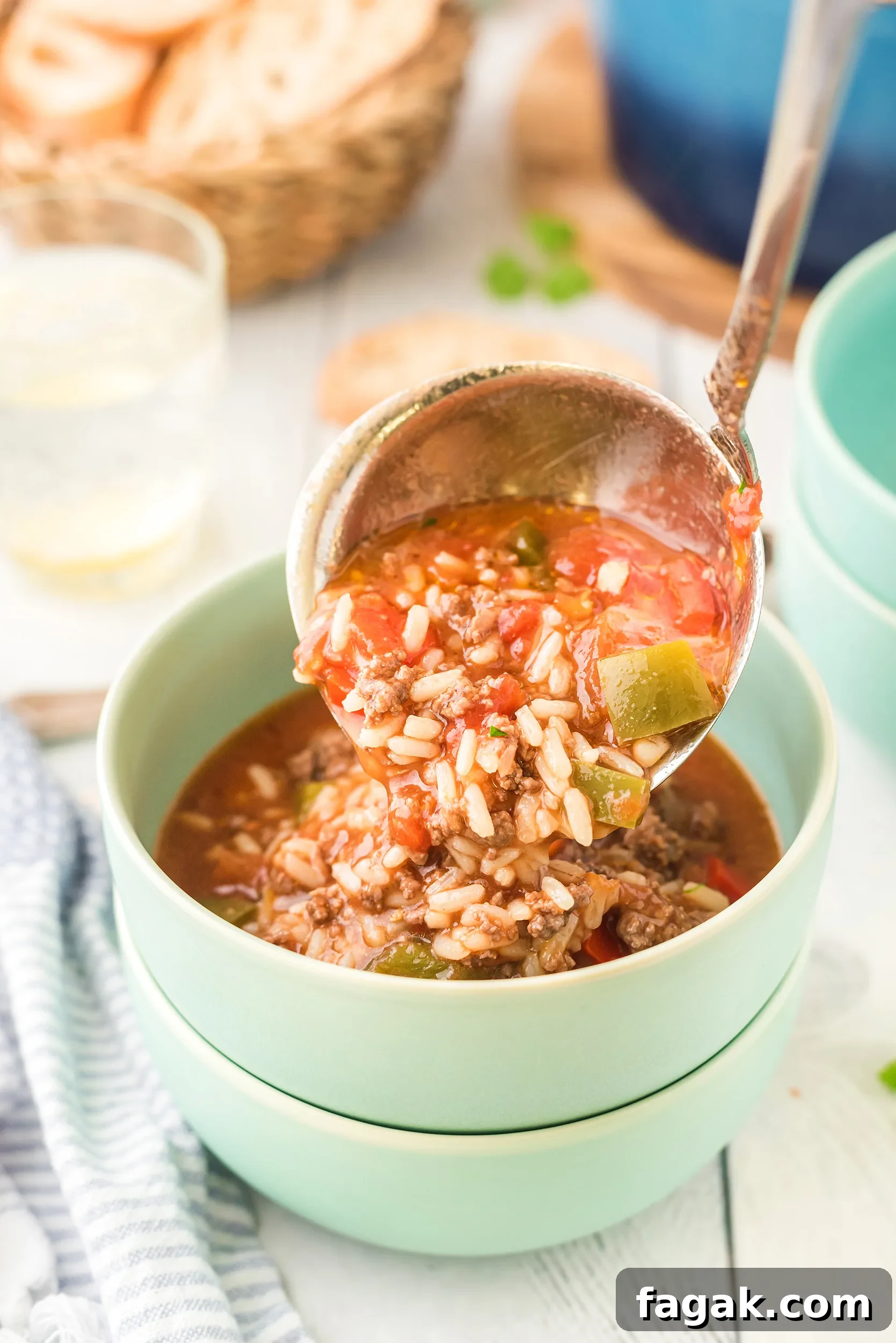 stuffed pepper soup being ladled into a mint green bowl