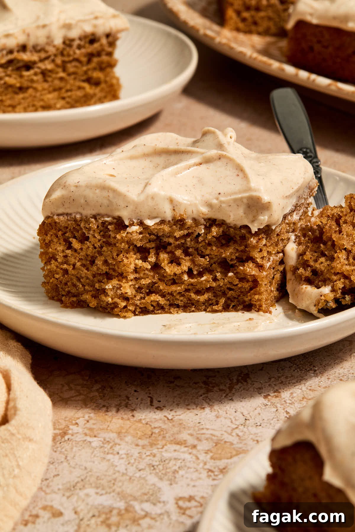 A piece of chai cake on a plate with a forkful removed and other pieces on plates in the background.