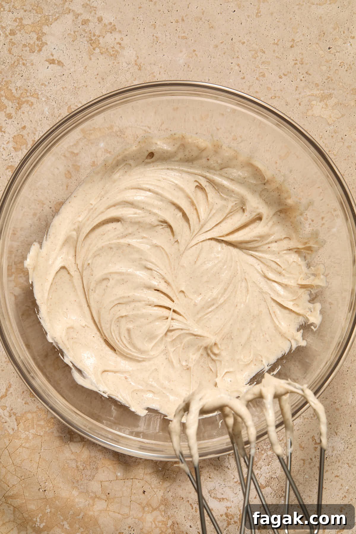 Frosting whipped together in a glass bowl with beaters in the frame.