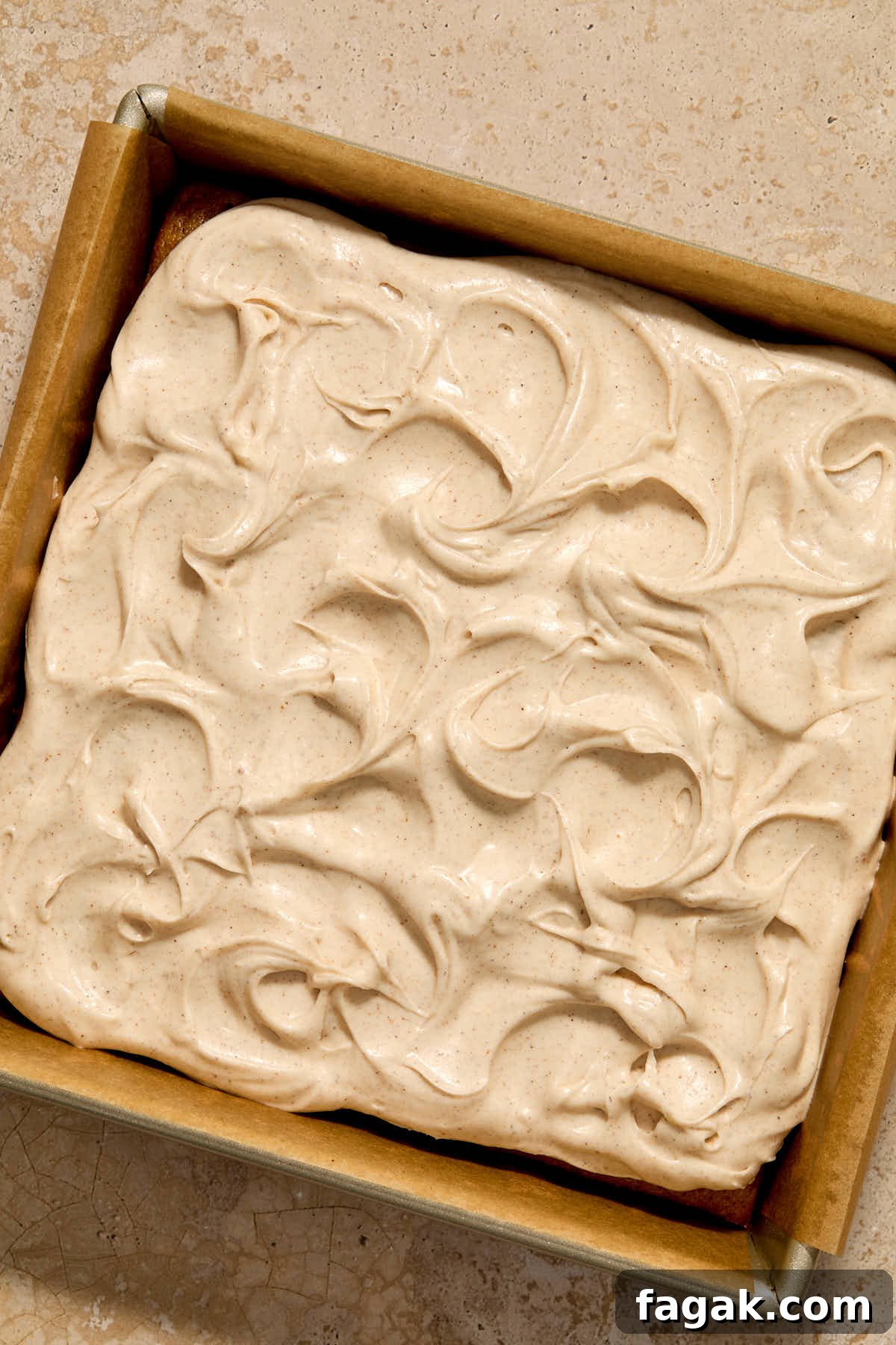 Frosting spread out on top of the cake in the pan.
