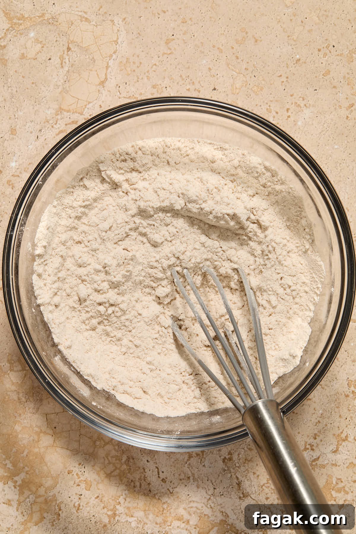 Dry cake ingredients whisked together in a glass bowl.