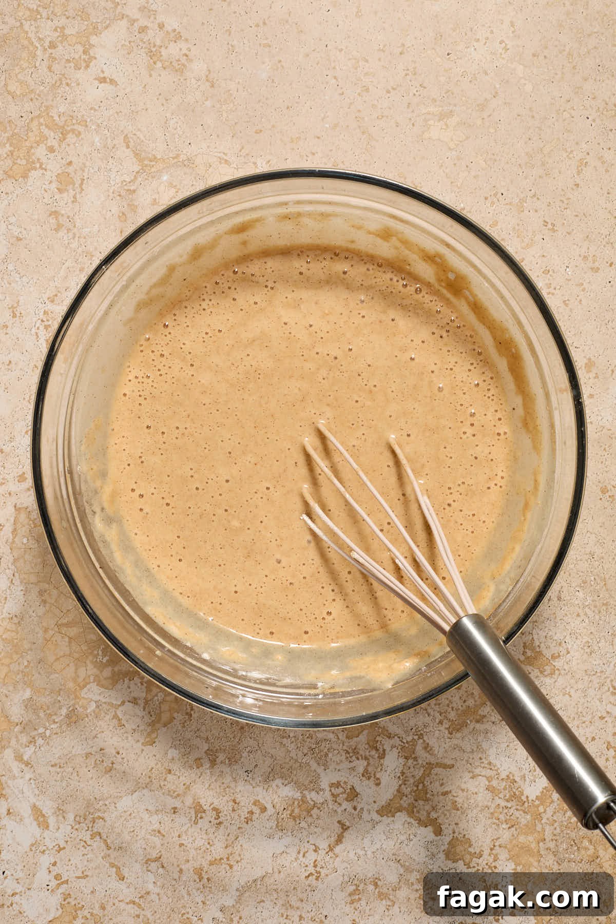 Batter mixed together in a glass bowl with a whisk.
