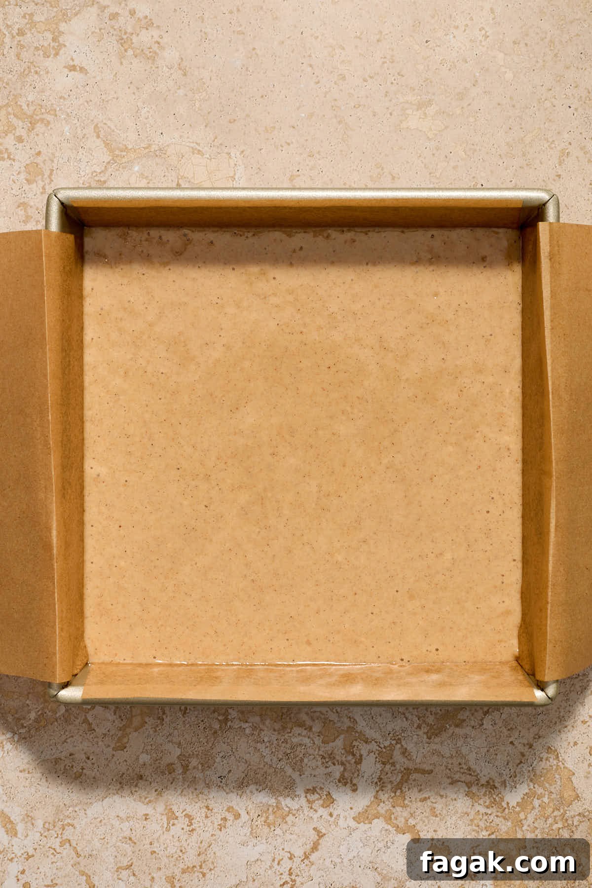Batter spread out in the prepared square cake pan.
